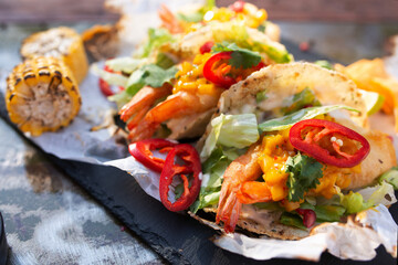 row of Tasty spicy and healthy Mexican street tacos served with various vegetables and salsa with chicken meat, beans   on slate with carne asada and al pastor in corn tortilla top view 