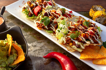 row of Tasty spicy and healthy Mexican street tacos served with various vegetables and salsa with chicken meat, beans   on slate with carne asada and al pastor in corn tortilla