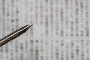 Calligraphy fountain pen on Japanese newspaper background with blurry abstract characters, backdrop...