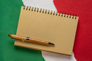 blank notebook against paper abstract in colors of national flag of Italy (green, white and red),...