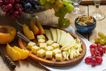 An appetizer of various types of cheese, grapes and walnuts, served with wine. Rustic style.