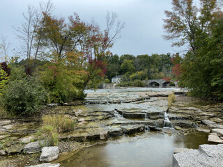 Fototapeta na wymiar Small waterfall and a stone bridge over a river