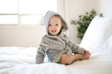 Obraz na płótnie Canvas portrait of beautiful child wearing bathrobe lying on bed and smile after shower