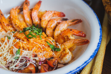 Traditional bright shrimp risotto in a bowl on a table in a restaurant with a beautiful decor in a dark key close-up.