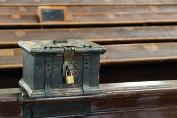 The church money box mounted on a pew in the church