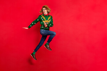 Photo of funky ginger guy jump move run look back scream wear specs ugly sweater isolated red color background