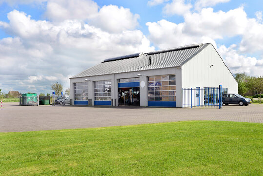 A car workshop or garage with doors open and cars on the forecourt.