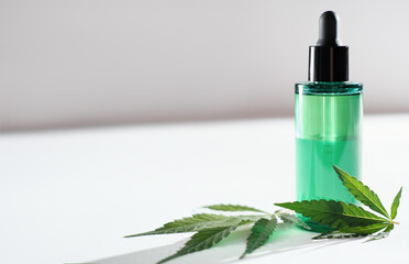 CBD facial oil with cannabis extract for a natural skin treatment. natural herbal cosmetic, skin treatment concept. marijuana leaves next to green bottle