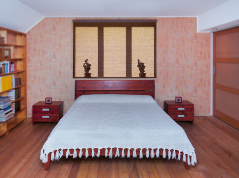 Bedroom interior with large bed, furniture and bedside tabel. Shadows on roller blind.