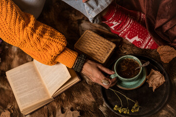 Beautiful woman in orange sweater reading a book and enjoying her coffee