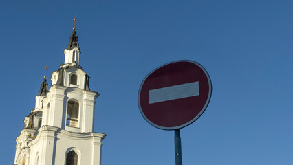 Fototapeta na wymiar Round traffic sign No entry red and white on the blue sky and orthodox church. Space for text. Church ban concept.