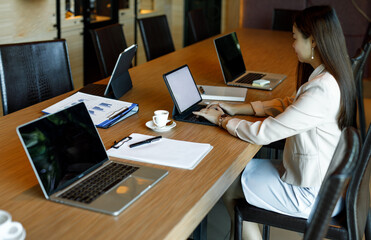Smiling Asian young businesswoman working on laptop in a modern office
