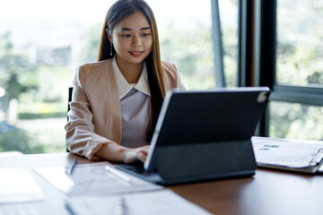 Smiling Asian young businesswoman working on laptop in a modern office