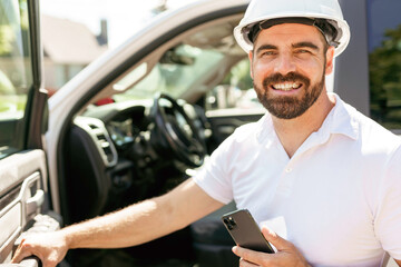 Man engineer builder wearing a white hard hat, shirt in front of his pickup using cellphone © Louis-Paul Photo
