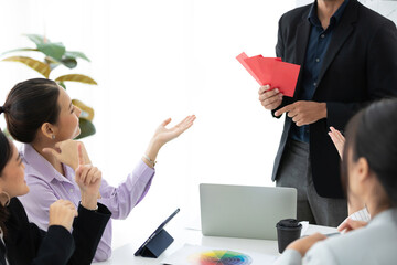 boss or manager giving cash bonus in red envelope to employee in meeting room