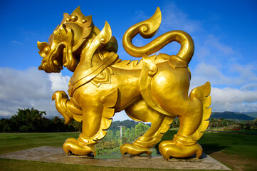 Singha or Lion golden statue on blue sky background in chiang rai thailand.