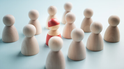 A red wooden figure standing with a team to influence and empowerment. Concept of leadership, successful competition winner and Leader with influence and Social distancing for a new normal lifestyle.
