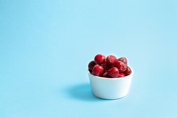 Frozen cherries in a white bowl on a blue background