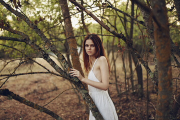 Naklejka na ściany i meble pretty woman in white dress near trees summer vacation fresh air