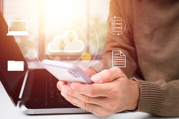 As an idea, a businessman works with a Cloud Computing diagram using a modern mobile phone and...