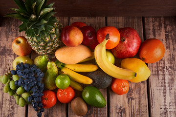 Mix of fresh juicy colorful exotic tropical fruits on wooden background top view