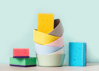 Washing dishes concept. Various bowls and sponge for washing dishes on a blue background. Copy space for text.