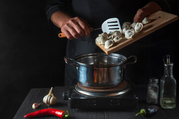 Professional chef cooks meat dumplings in a saucepan in the restaurant kitchen. Close-up of the hands of the cook during work. Free advertising space.