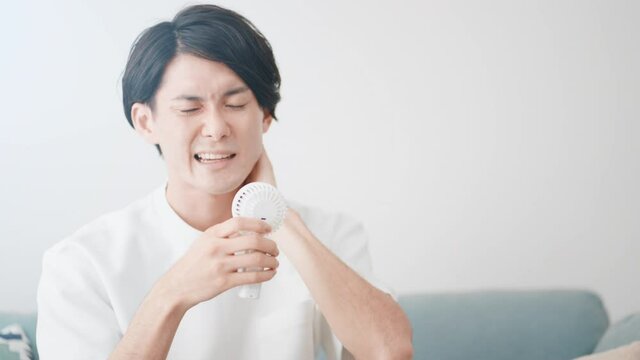 ハンディ扇風機で涼しんでいる男性