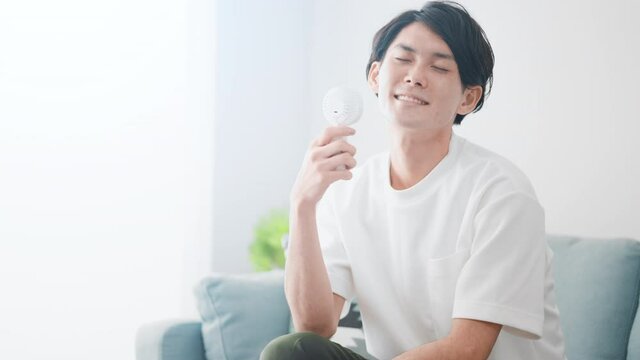 ハンディ扇風機で涼しんでいる男性