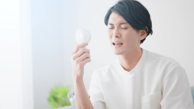 ハンディ扇風機で涼しんでいる男性