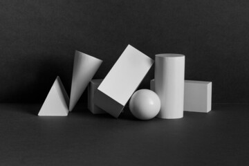 Platonic solids figures geometry. Abstract geometrical objects still life composition. Three-dimensional rectangular prism, cylinder pyramid cube, sphere on black gray background - 458978141