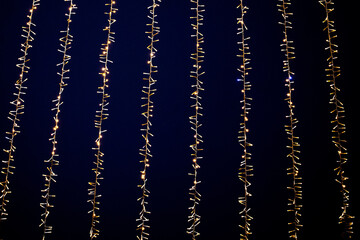 Electric light chain garland on dark background. Thousand small light bulbs, festive garland illuminate night sky.