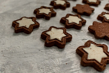 Christmas chocolate cookies in the shape of a star with white glaze on a light blurry background.