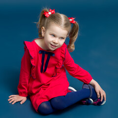 Cute gray eyed girl in red dress sitting on floor