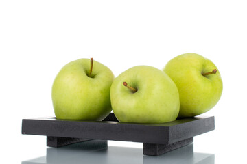 Three ripe green apples on a tray of wood, close-up, isolated on white.