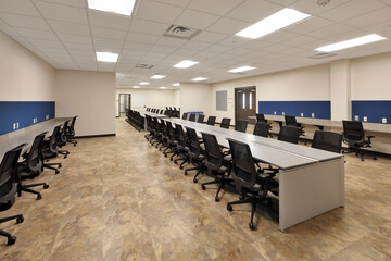 Conference room in modern office building with long desks and black office chairs
