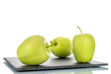 Three ripe green apples on a slate stone, close-up, isolated on white.
