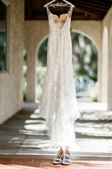 White wedding dress hanging on the terrace of house Beautiful wedding dress shoes Gorgeous wedding dress on a hanger dress hanging on a hanger outside white arch background