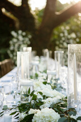 Wedding outdoor table set up Beautiful garden wedding venue wedding table design  White candle on the dining table. The candle is placed in a special glass container The background is blurred