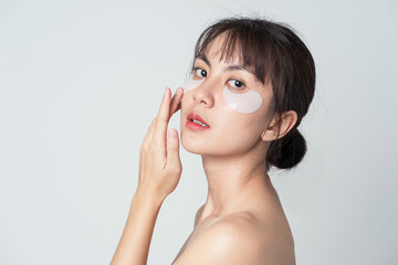 Obraz na płótnie Canvas Portrait posing Asian woman applying patches mask under eyes for anti wrinkles and eye dark circles.