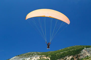 Tandem orange paragliding against a blue sky, sunny day