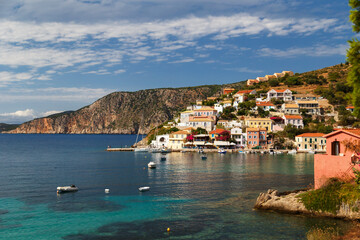 Naklejka na ściany i meble A view at blue bay, sea-front street of Asos village, greek colorful houses and turquoise Ionian Sea water. Luxury summer vacation and holiday at Cephalonia island. Greek island travel background.
