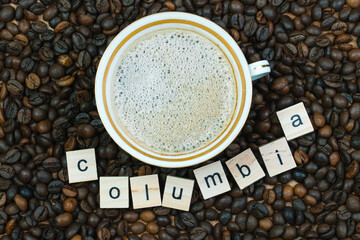 Top view of a cup of coffee on a background coffee beans with the inscription Columbia. Production, export and import of coffee
