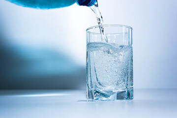 Pouring mineral water into a glass beaker.