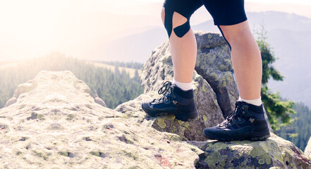 Tourist legs in hiking boots. Trekking shoes. Against the background of mountains and rocks.