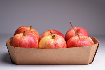 Fresh red apples  in a paper container. Fresh red apples  in box on grey background.