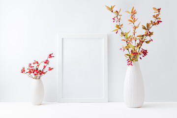 Home interior with decor elements. Mockup with a white frame, colorful autumn leaves and red berries in a vase on a light background