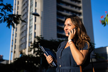 business woman calling with mobile on the street with office building in the background