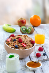 Healthy breakfast with bowl of cereal, orange juice, milk, and fruits.