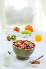 Healthy breakfast with bowl of cereal, orange juice, milk, and fruits.